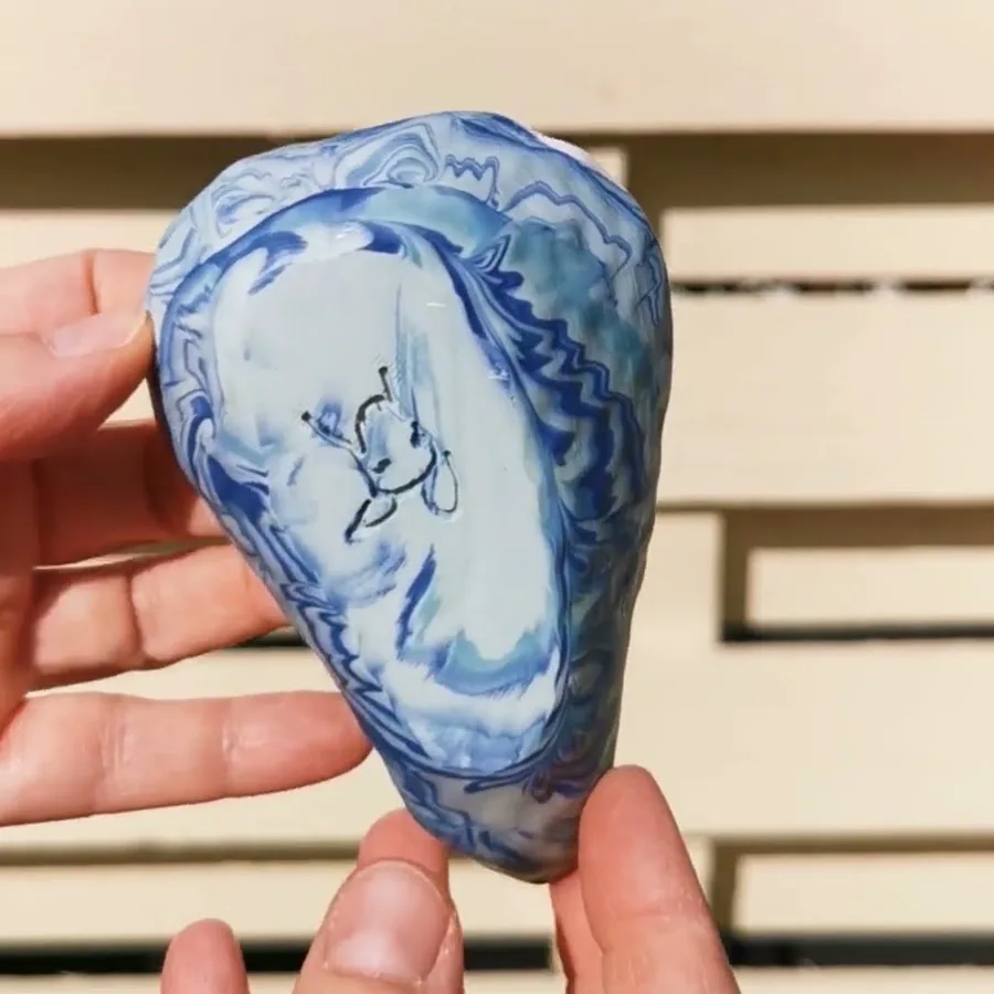 Video of a hand turning a blue and white marbled ceramic bowl in the sun
