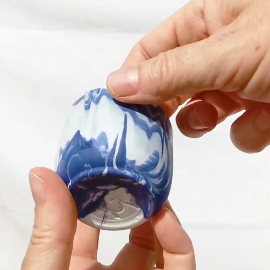Video of a hand turning a blue and white marbled ceramic cup