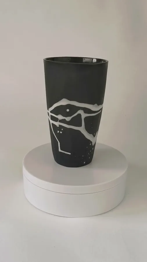 Video of a black ceramic vase with white line drawing turning on a plinth